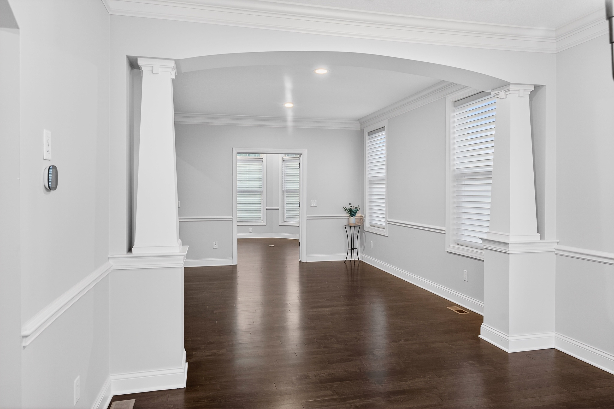 Formal entryway with arched columns, crown molding, and dark walnut hardwood floors