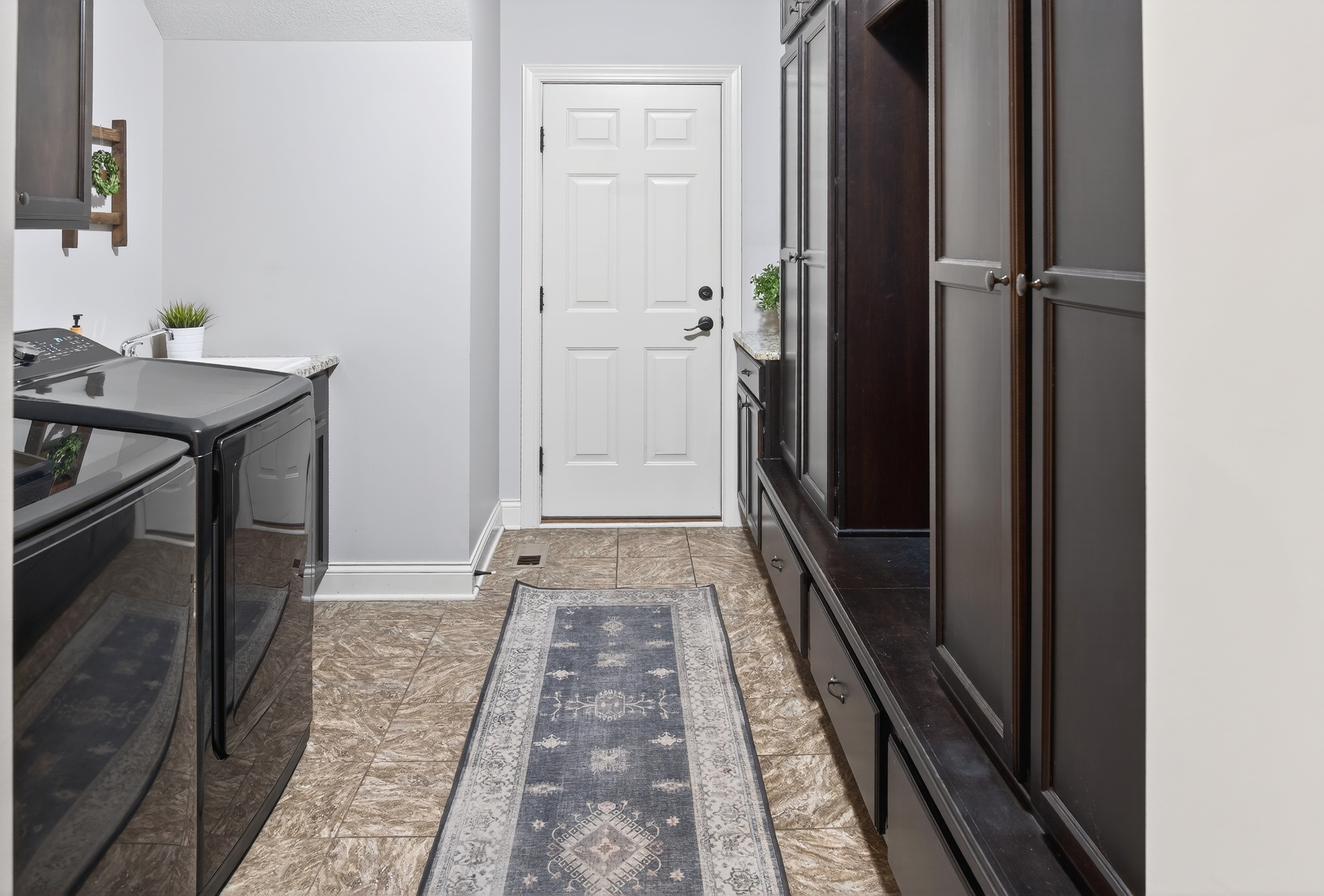Laundry and mud room with dark cabinetry and tile floor